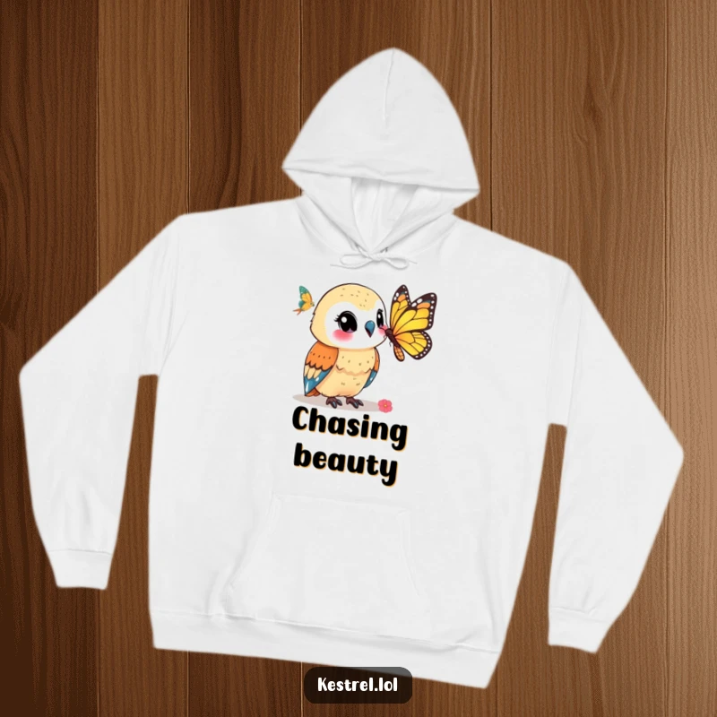 Funny kestrel hoodie illustrating a smiling kestrel character watching a butterfly, offering warmth and serene humor.