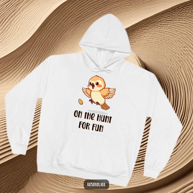 Funny Kestrel Hoodie: A playful kestrel energetically chases a bouncing seed, its focus and excitement humorously captured.