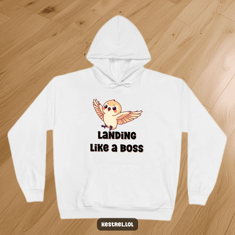 Funny kestrel hoodie illustrating a small kestrel character making a graceful landing, offering warmth and sophisticated humor.