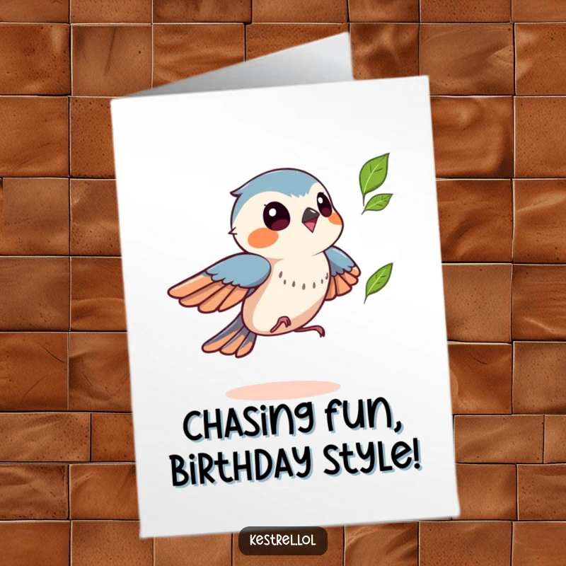 Funny Free Printable Kestrel Birthday Card: Kestrel playfully chasing a fluttering leaf, embodying birthday fun and lightheartedness.