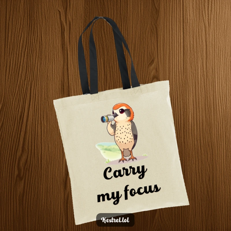 Funny kestrel tote bag with a curious bird using tiny binoculars to scan a landscape. A humorous and practical accessory.